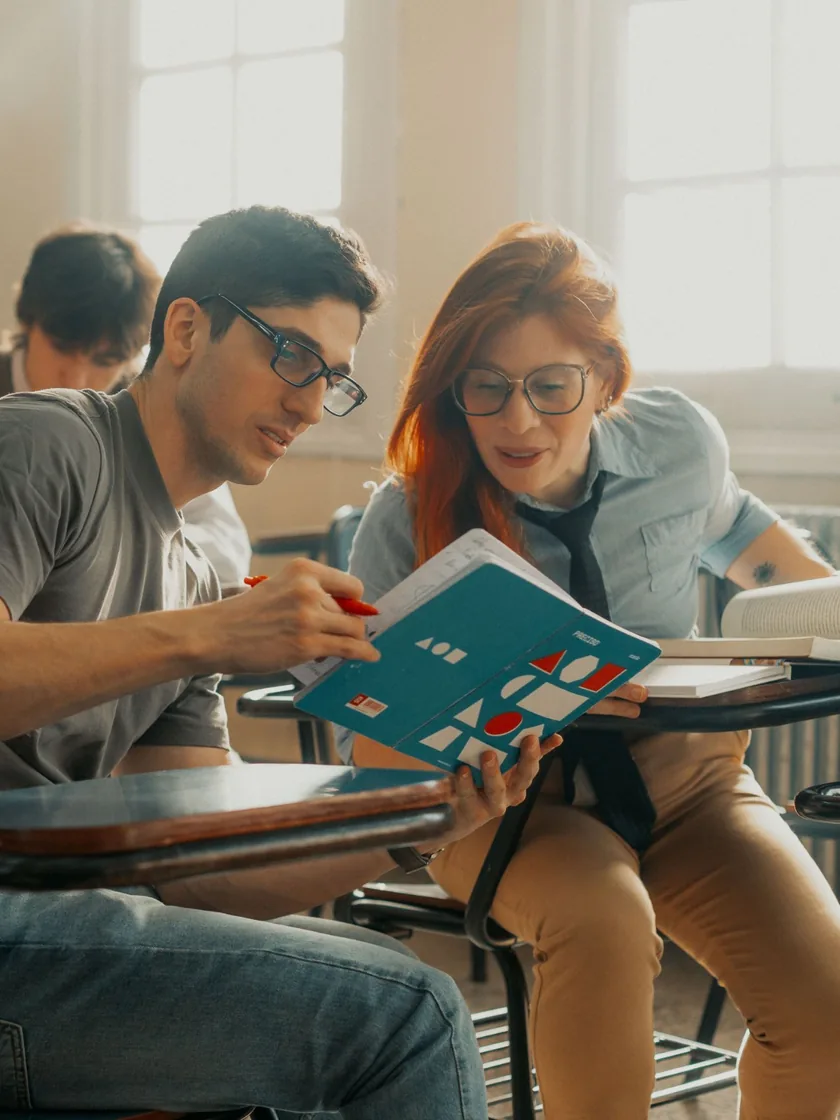 Dos estudiantes comparten un cuaderno durante una clase en el aula