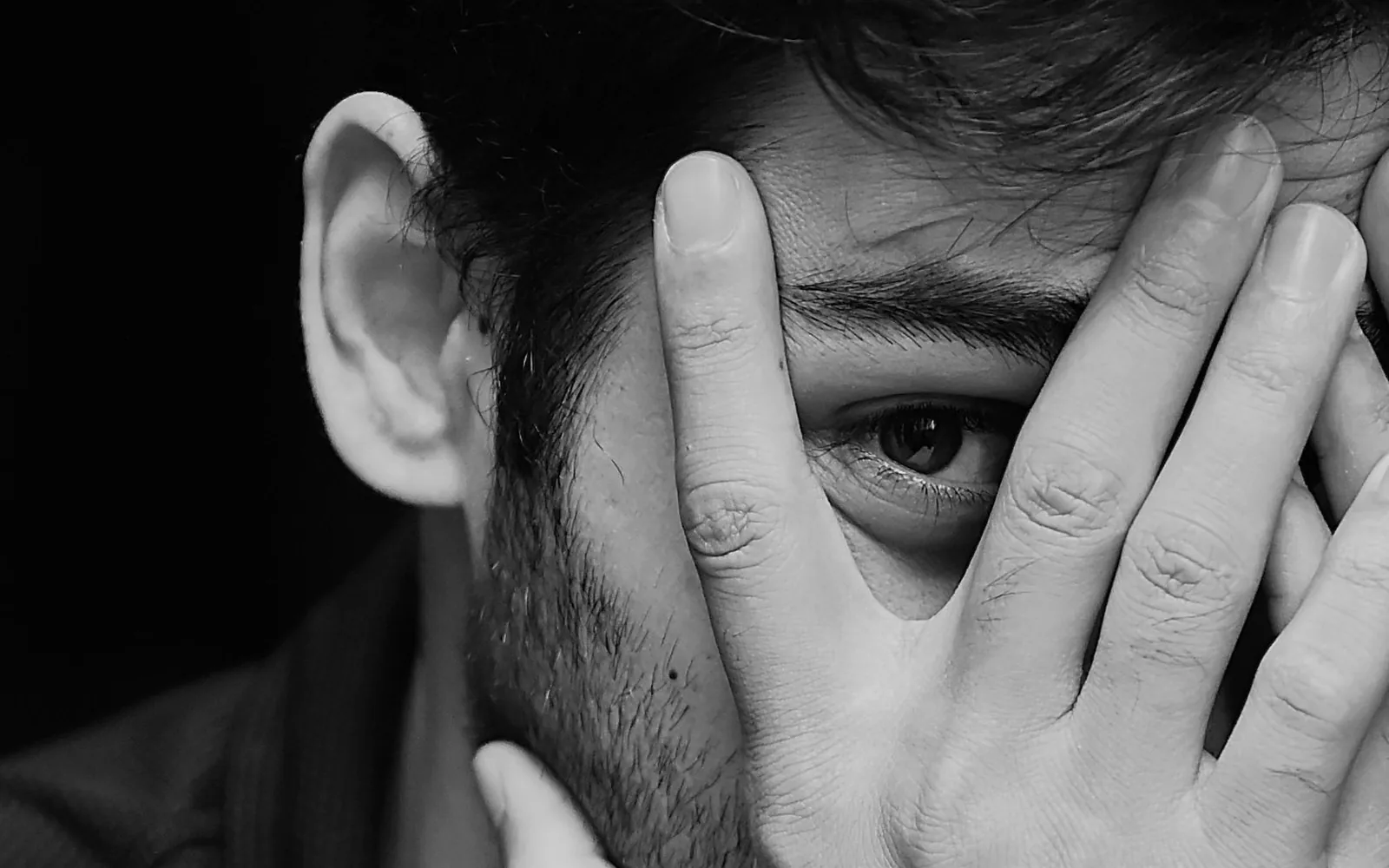 Padre agachado a la altura de su hijo pequeño mientras conversa con él.