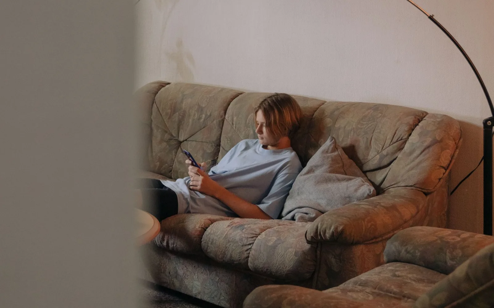Mujer mirando la pantalla de su móvil mientras está sentada en el sofá.